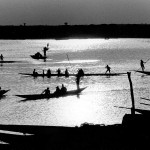 Mali, Mopti. 1986. Rowers navigate their canoes with cargo and passengers across the river Niger at sunset.