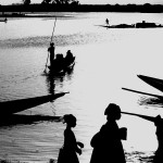 Mali, Mopti. 1986. Rowers navigate their canoes with cargo and passengers across the river Niger at sunset.