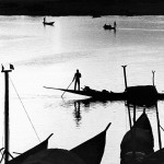 Mali, Mopti. 1986. Rowers navigate their canoes with cargo and passengers across the river Niger at sunset.