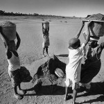 Guinea-Bissau, K3 village, on the outer marshes of the Cacheu river. 2005. A family carries buckets with silt from the river forelands that were once fertile rice fields. At home, they filter and boil the silt with water and obtain good quality salt.