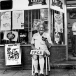 Zimbabwe, Mutare. 1993. An elderly man sits in front of a bottle store and raises funds for the SPCA, the Society for the Prevention of Cruelty to Animals.