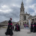 Portugal, Estremadura, Cova de Iria, Fatima. 2017. Bishops walk in front of the Basilica of Our lady of Fatima after the departure of Pope Francis. A television screen shows his farewell.